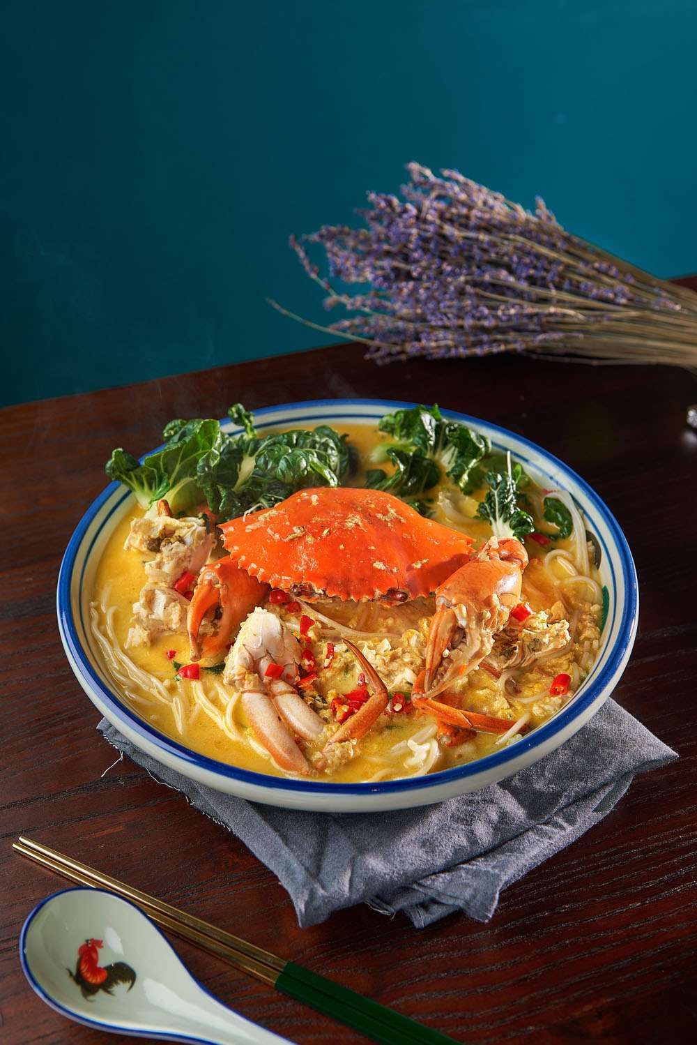 A whole crab in a creamy cheese sauce with bee hoon, a bowl of golden mantou beside it.