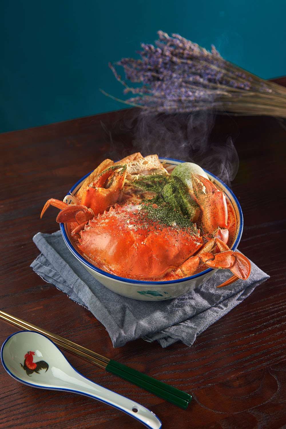 A whole crab sitting in a creamy yellow laksa broth with bee hoon and herbs.