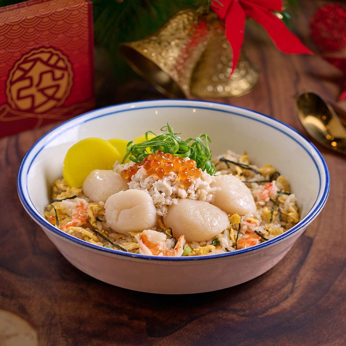 A bowl of seafood fried rice topped with scallops, crab meat, orange roe and pickled yellow radish.
